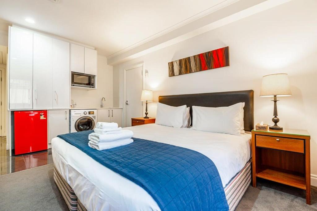 a bedroom with a bed and a red refrigerator at Cosy studio on Queen Street in Auckland