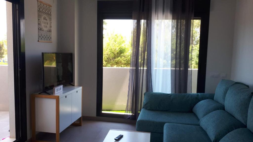 un salon avec un canapé bleu et une télévision dans l'établissement Neo Mediterráneo, à Barrio-Mar