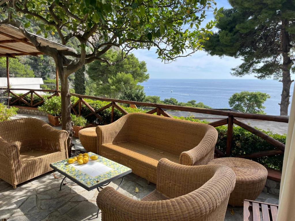 um pátio com cadeiras de vime e uma mesa com fruta em O’Sole em Capri