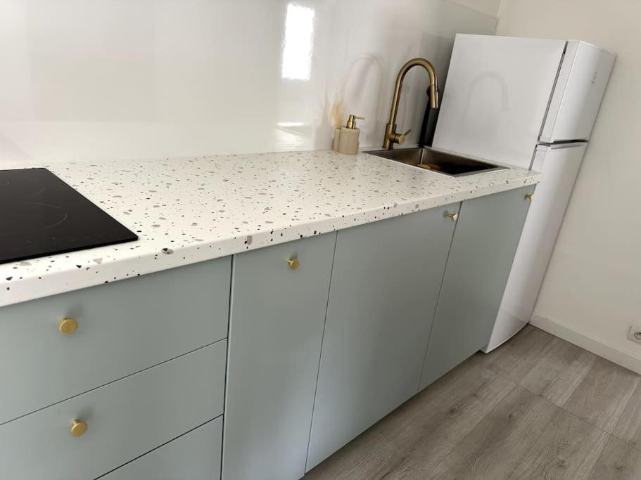 a white kitchen with a sink and a refrigerator at Little house (near Paris & Airport) in Drancy
