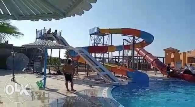 a person standing next to a water slide in a pool at شاليه للايجار بالساحل الشمالى in Marsa Matruh