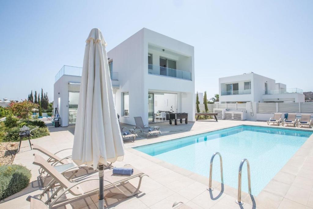 einen Pool mit Sonnenschirm und Stühlen und ein Haus in der Unterkunft Ferienhaus für 10 Personen in Protaras, Südküste von Zypern - b59033 in Protaras