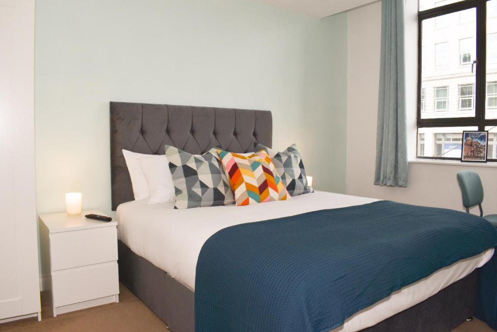 una camera da letto con un letto con una coperta blu e cuscini di Vibrant Serviced Apartment In Central Birmingham a Birmingham