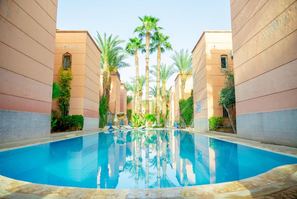 Riad The Moroccans Pool And Terrace في مراكش: مسبح في مبنى فيه نخيل