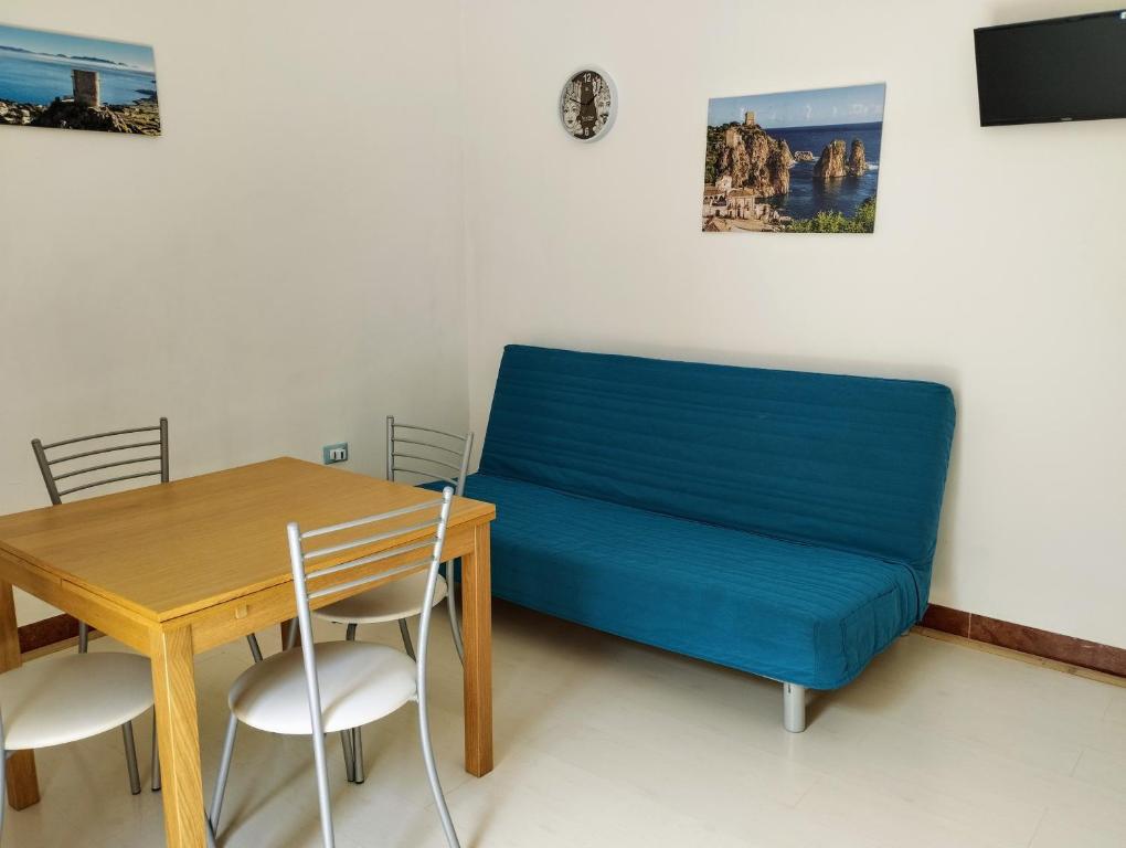 un letto blu in una stanza con tavolo e sedie di Appartamenti Blu Mare a Castellammare del Golfo