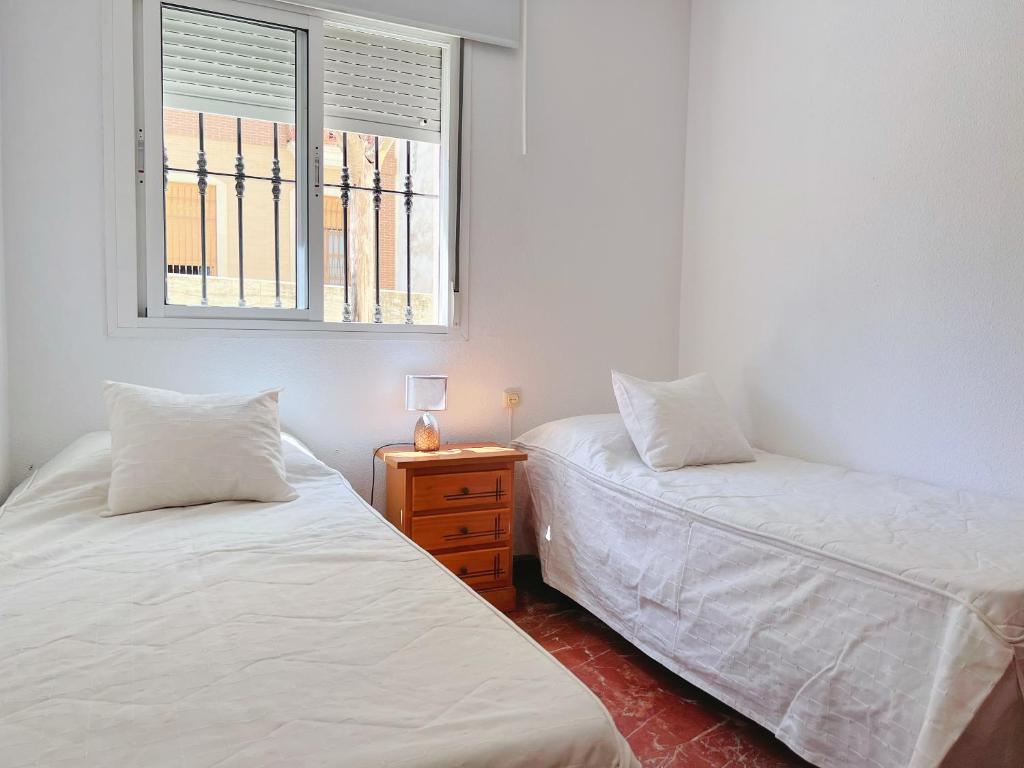 two twin beds in a room with a window at Habitación compartido Huelva centro in Huelva