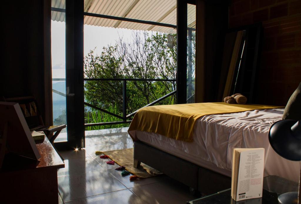 1 Schlafzimmer mit einem Bett und einem Balkon mit Aussicht in der Unterkunft Extraordinario chalet a 1h de Bta in San Antonio del Tequendama