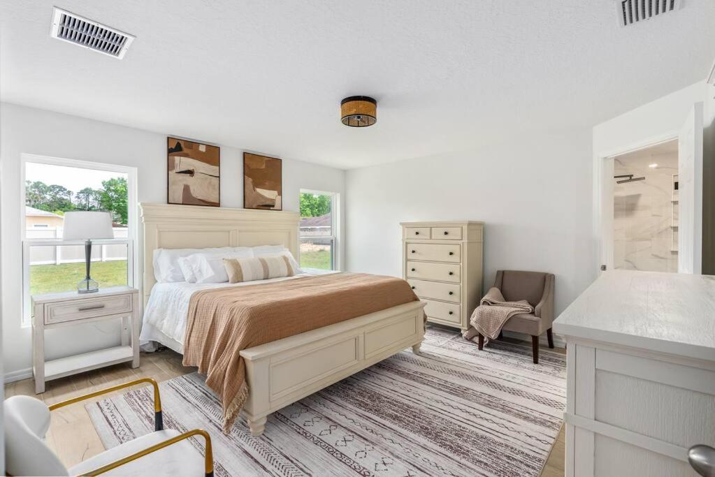 a white bedroom with a bed and a dresser at spacious 4-bedroom WITH KING BED in Palm Coast