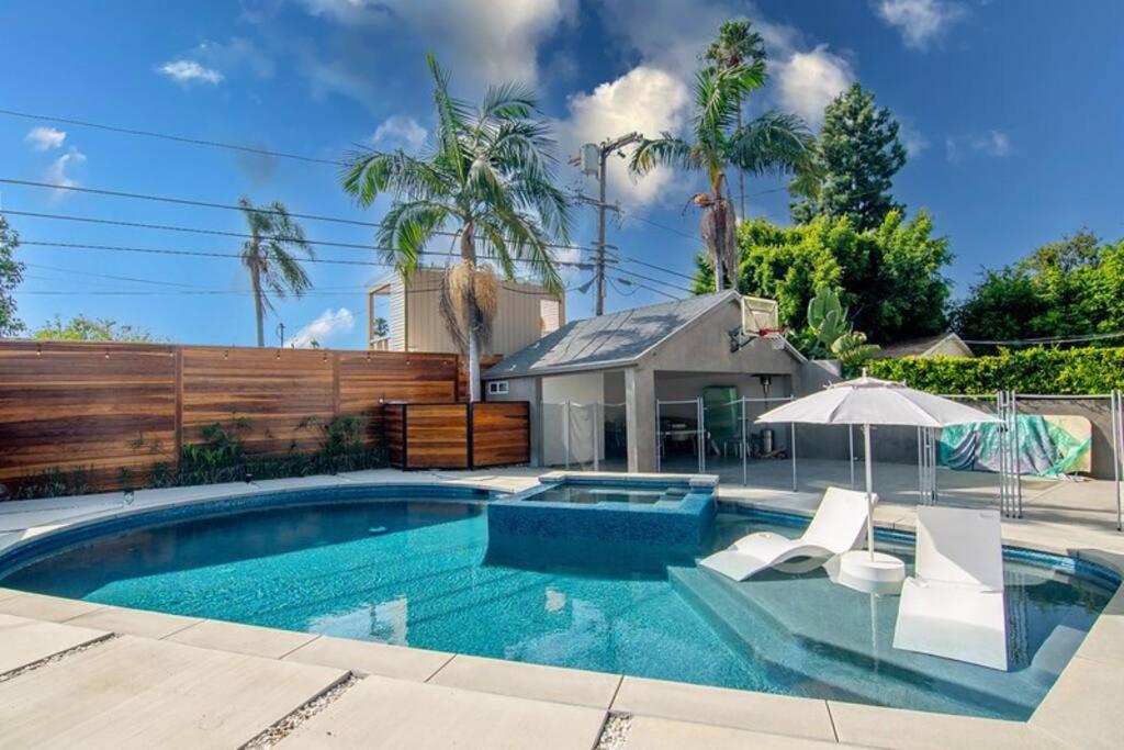 a swimming pool with chairs and an umbrella at Prestigious 5BR Mansion w/ Pool, Theatre & Jacuzzi in Los Angeles