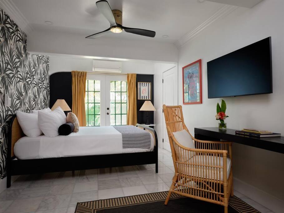 a bedroom with a bed with a fan and a chair at The Lehua Suite at the Historic Wailuku Inn Maui in Wailuku