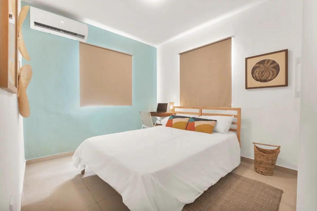 a bedroom with a white bed and a blue wall at OASIS Punta Cana Apartment in Punta Cana