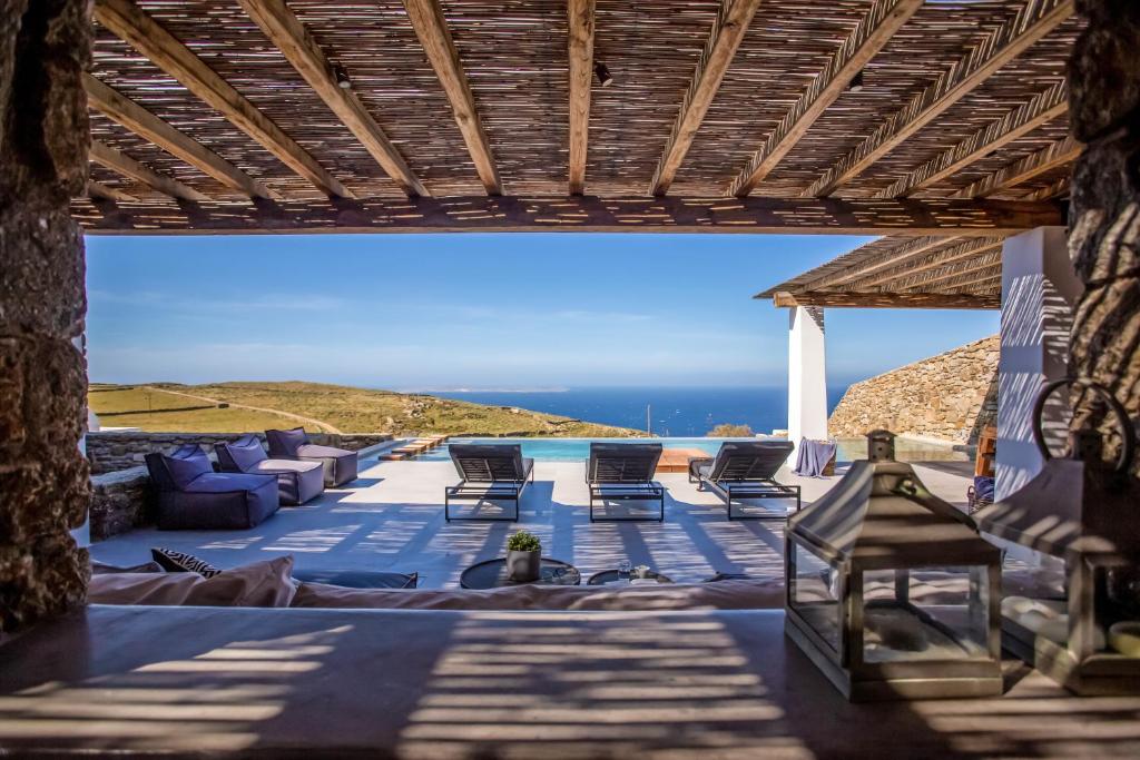 d'une terrasse avec des chaises et une vue sur l'océan. dans l'établissement AURA Seaview Sunset Pool Villa - Six Bedrooms, à Fanari