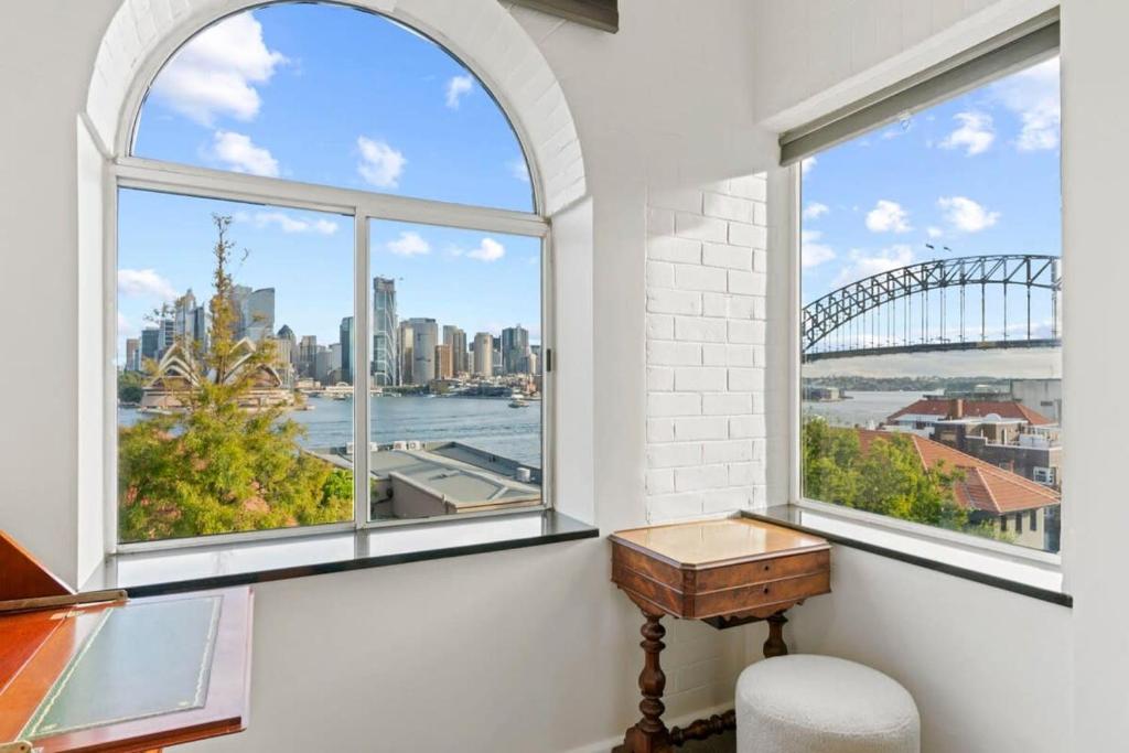 een kamer met ramen, een bureau en uitzicht op de haven van Sydney bij Lovely Apartment with Spectacular Views in Sydney