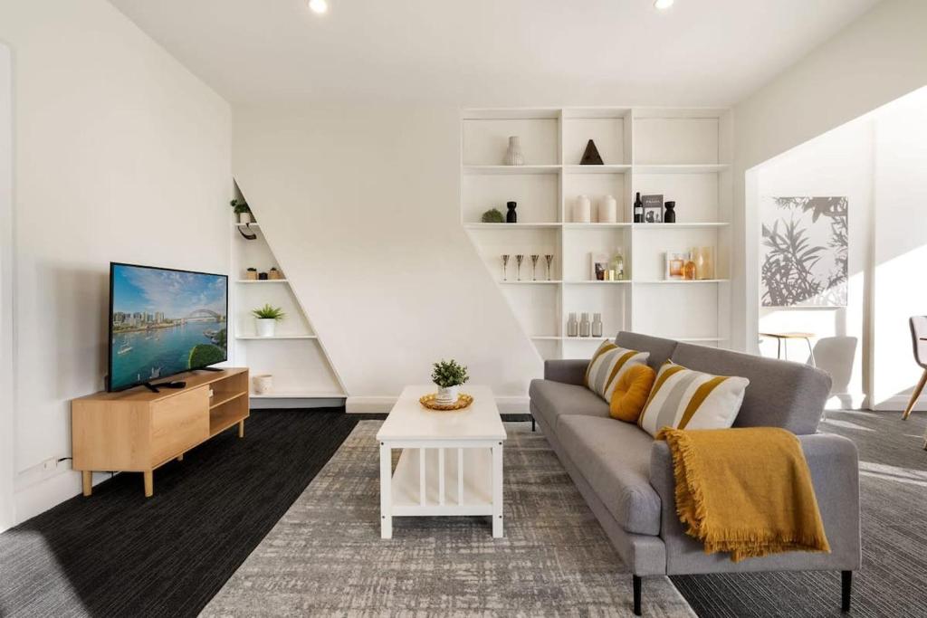 a living room with a couch and a tv at Top Floor Apartment with Harbour Views in Sydney