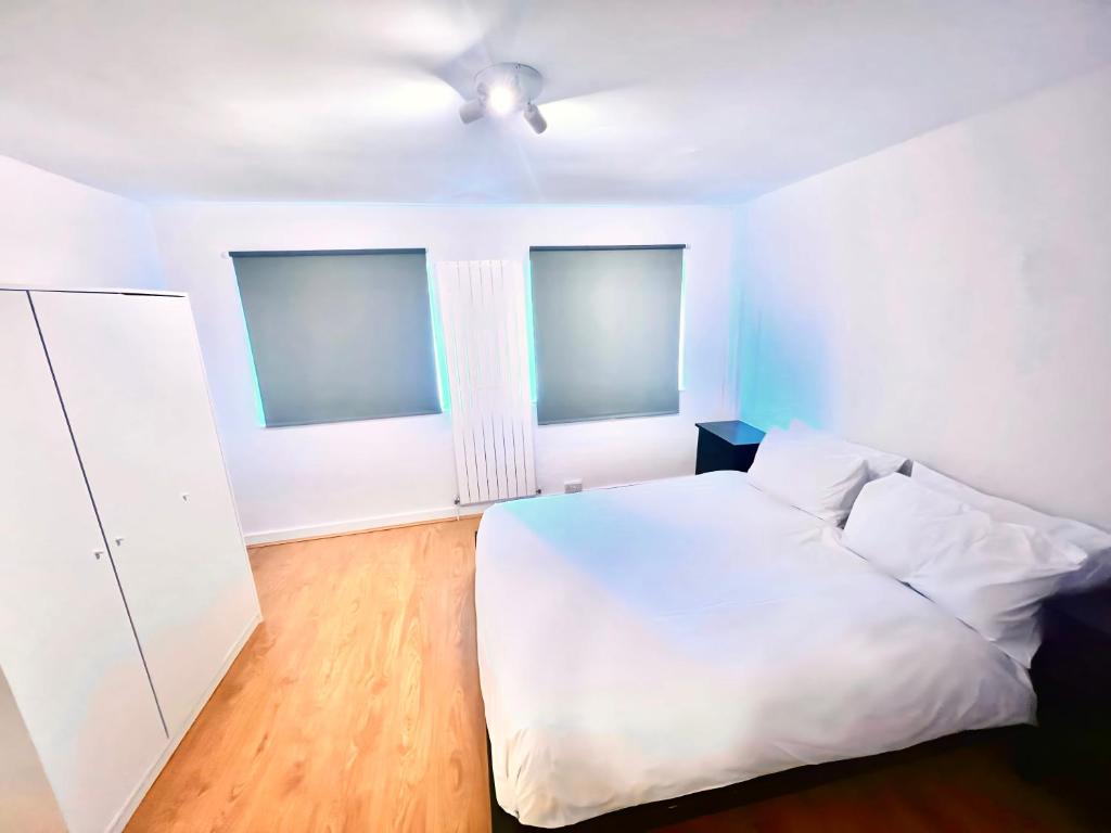1 Schlafzimmer mit einem weißen Bett und 2 Fenstern in der Unterkunft Hickory Haven in Borehamwood