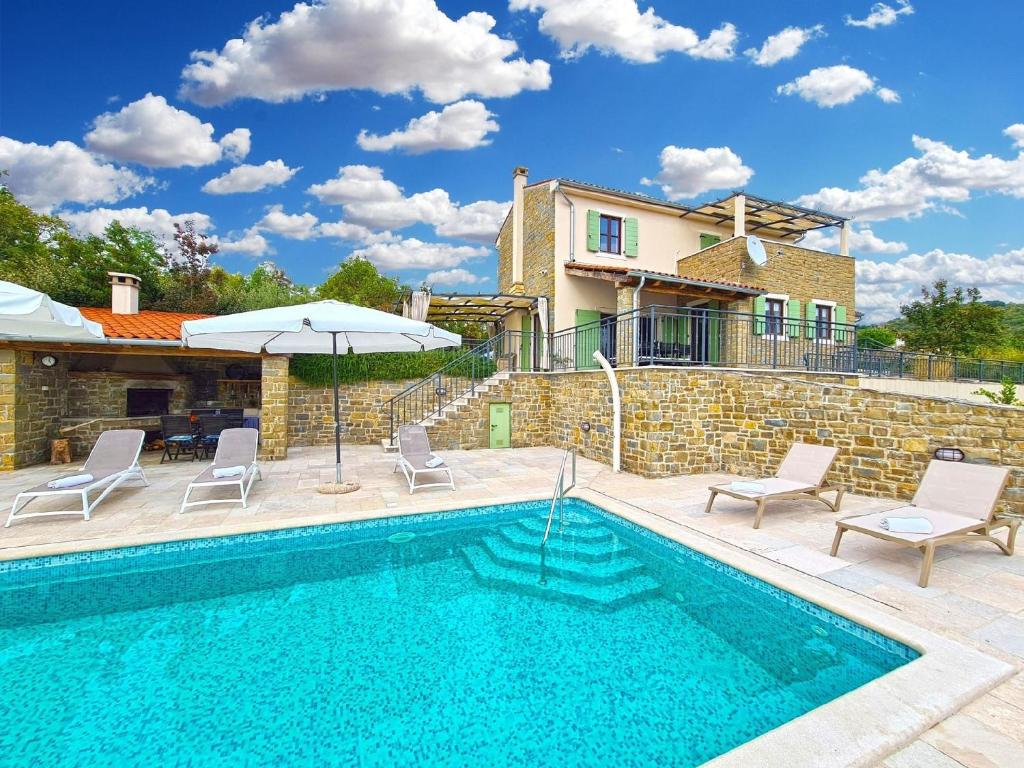einen Pool mit Stühlen und einem Sonnenschirm neben einem Haus in der Unterkunft Ferienhaus für 10 Personen in Bartolici, Istrien Binnenland von Istrien in Motovun