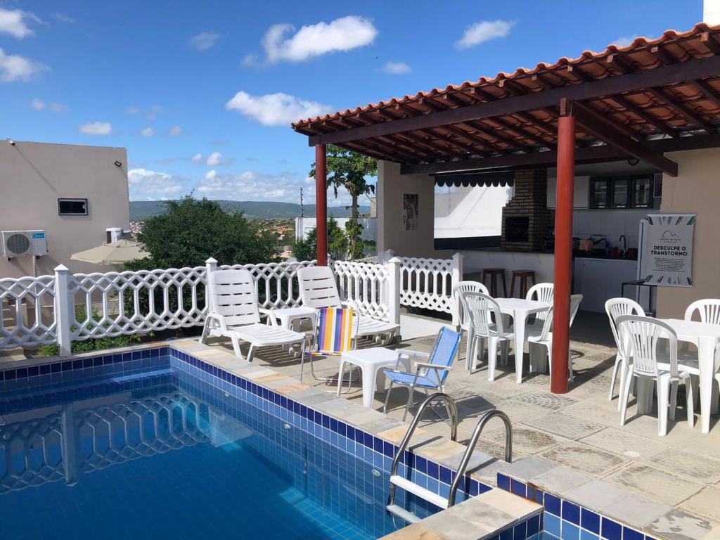 uma piscina com cadeiras brancas e um pavilhão em Flat Rainha da Serra em Bezerros