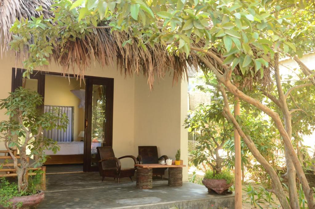 une chambre avec un lit, une table et des arbres dans l'établissement Red Flower Cottages Homestay, à Hội An