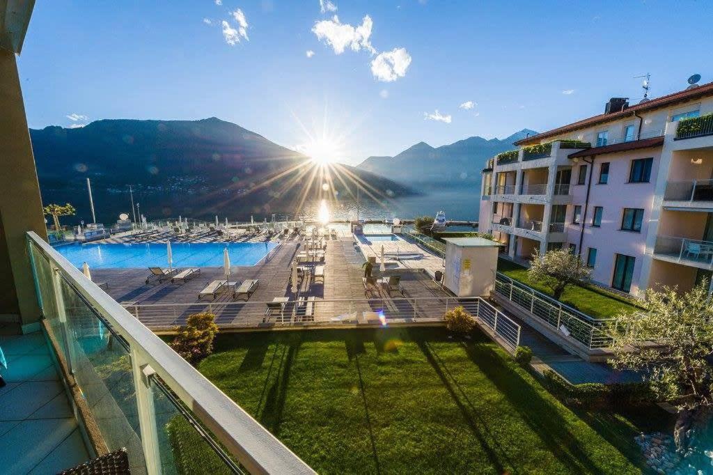a view from the balcony of a building with the sun shining at Modern 3 bedroom apartment on Lake Maggiore in Maccagno Inferiore