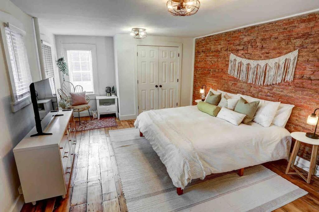 a bedroom with a large bed and a brick wall at Beautiful Boho Villa on Vine in the heart of Lancaster in Lancaster