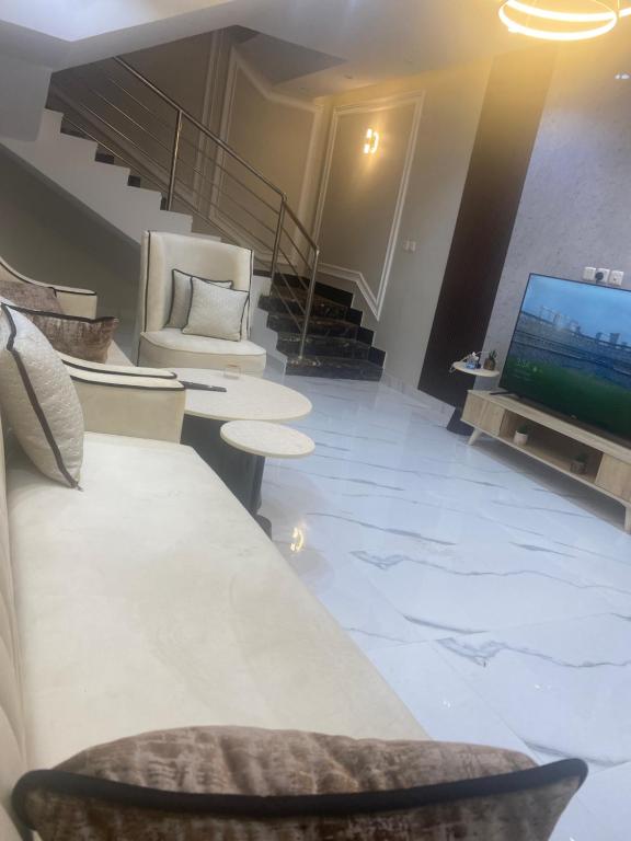 a living room with a television and a couch and chairs at فله روف خاصه in Tabuk