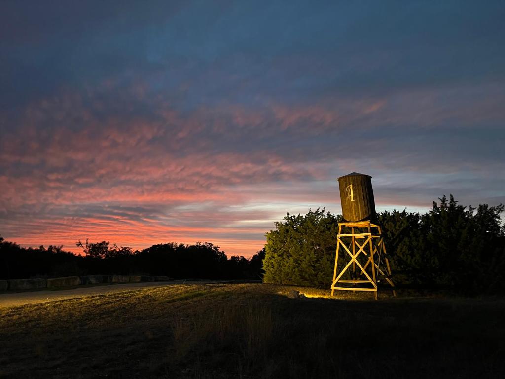 a tower in the middle of a field at sunset at The Alexander at Creek Road in Dripping Springs