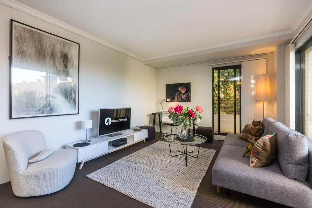 a living room with a couch and a tv at 1 Bedroom Apt with Parking Pool and Gym in Sydney