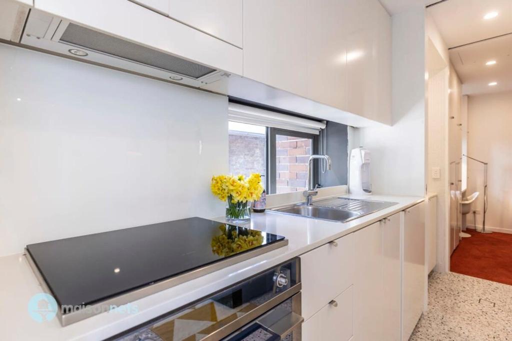 a kitchen with white cabinets and a sink at Darlinghurst Apt W A C Balcony Only A Walk To CBD in Sydney
