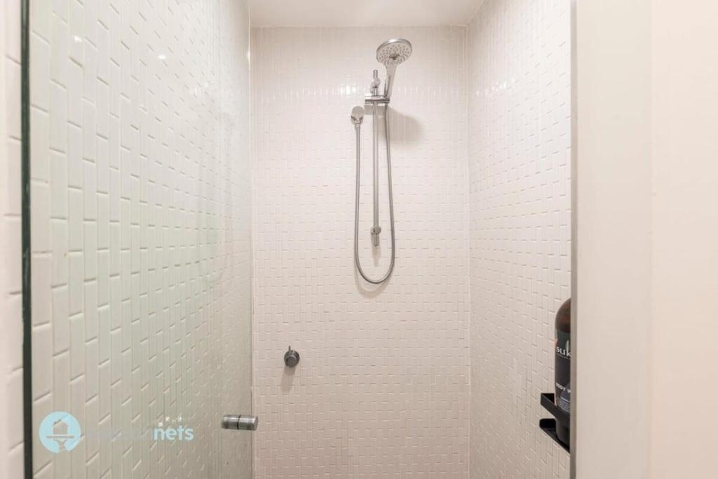 a shower in a bathroom with a white tiled wall at Darlinghurst Apt W A C Balcony Only A Walk To CBD in Sydney