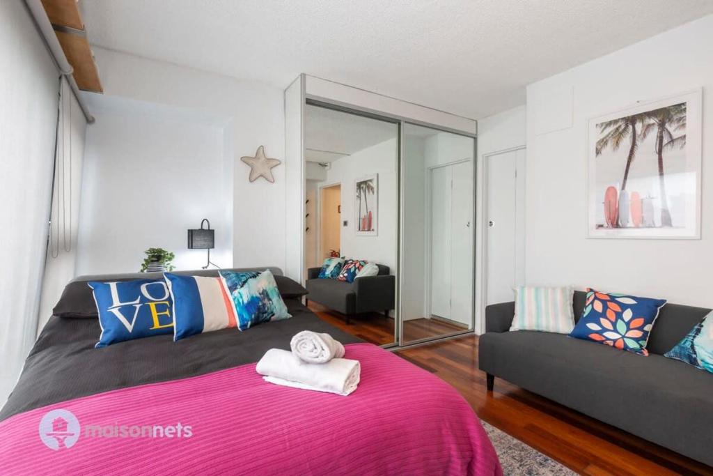 a bedroom with a pink bed and a couch at Studio Gem With Rooftop Space Prime Location in Sydney