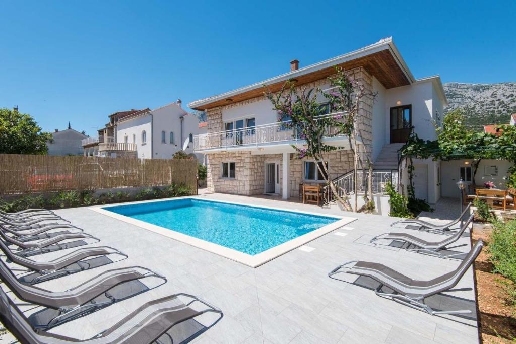 een zwembad met stoelen en een huis bij Ferienhaus für 13 Personen in Orebić, Dalmatien Süddalmatien in Orebić