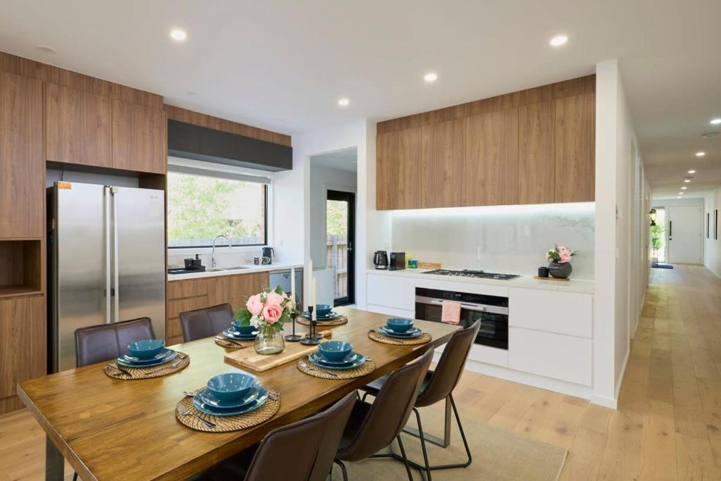 cocina y comedor con mesa de madera y sillas en 5 Bedroom 5 Bathroom Townhouse with Aircon en Melbourne