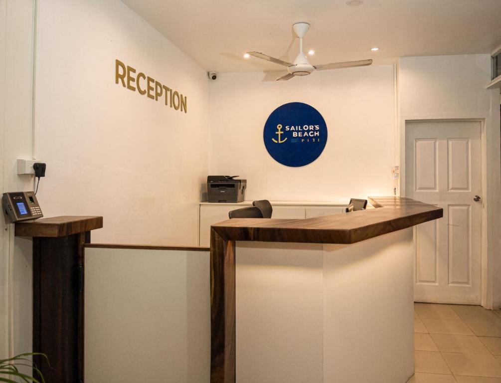 a reception desk in a room with a ceiling fan at Sailors Beach Fiji in Nadi