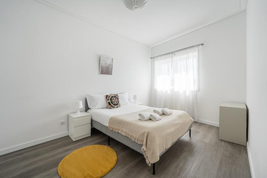 ein weißes Schlafzimmer mit einem Bett und einem Fenster in der Unterkunft GuestReady - A sunny moment in Porto in Porto