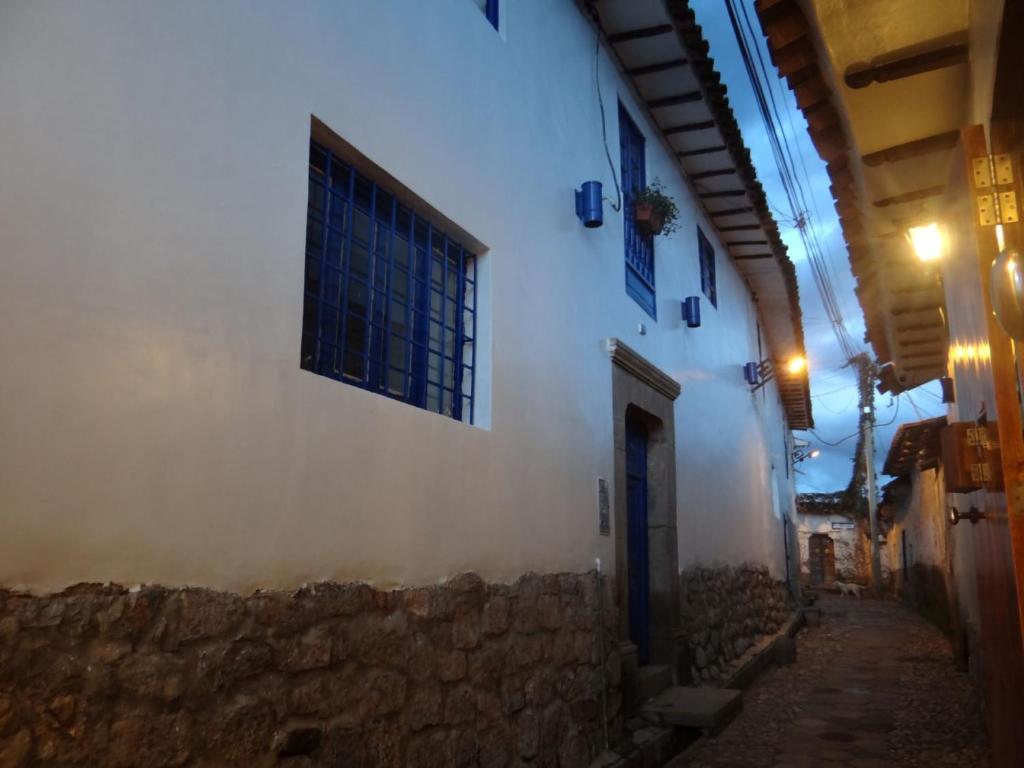 an alley with a white building with a window at Haku Hostel in Cusco