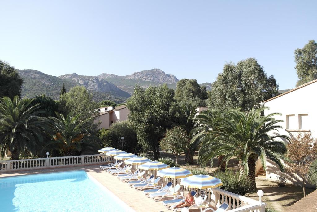 - Piscina con tumbonas y sombrillas en Residence Thalassa en Calvi