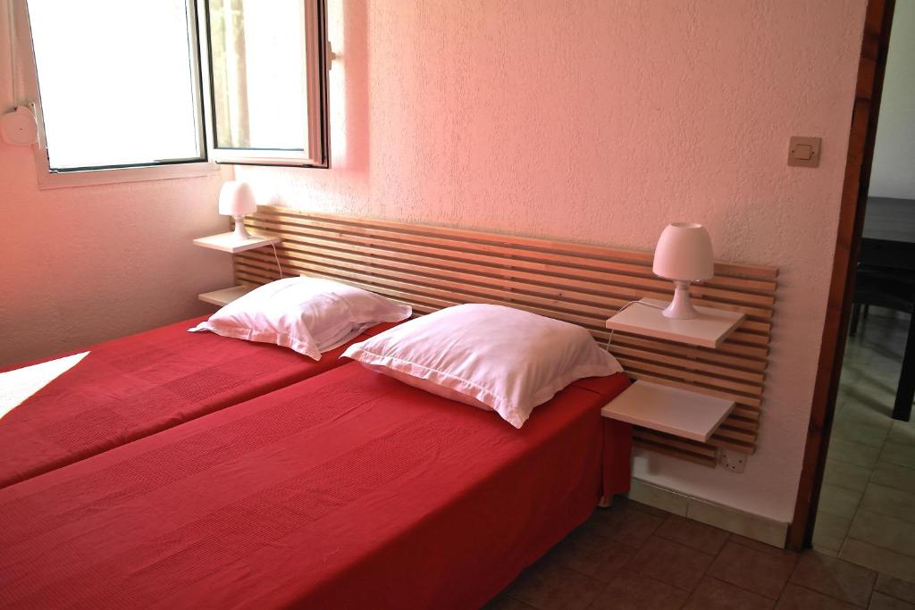 a bedroom with a red bed with two pillows and a window at Residence Thalassa in Calvi