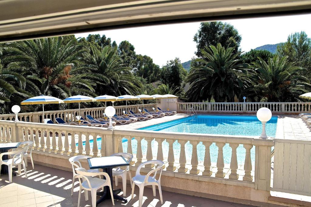 a balcony with a swimming pool with chairs and umbrellas at Residence Thalassa in Calvi