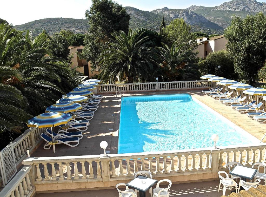 a swimming pool with chairs and umbrellas at Residence Thalassa in Calvi