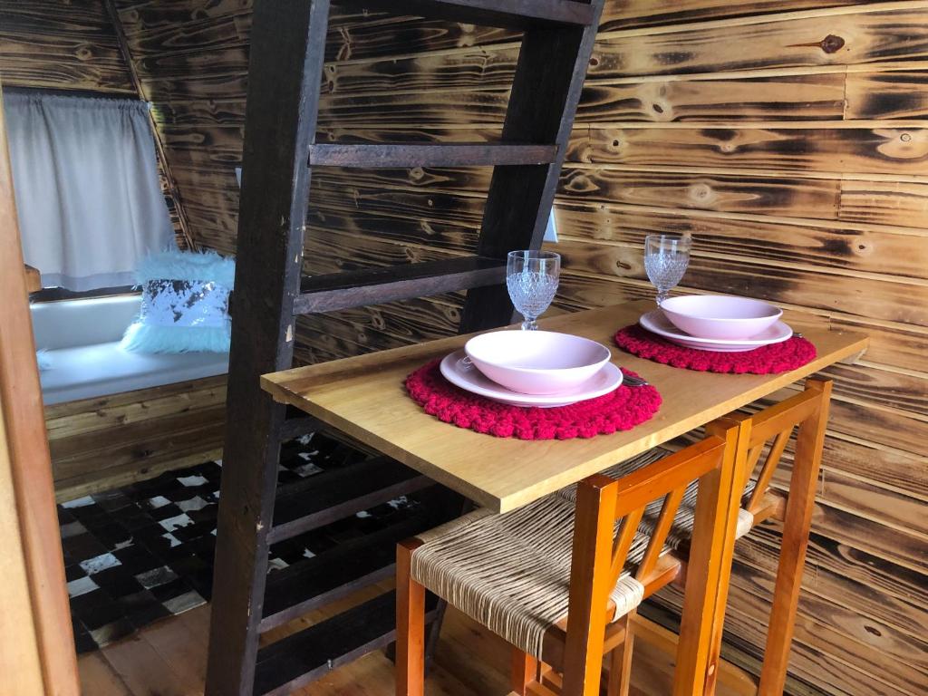 a wooden table with two plates and glasses on it at Pousada e sítio do Robinho in Timbe do Sul