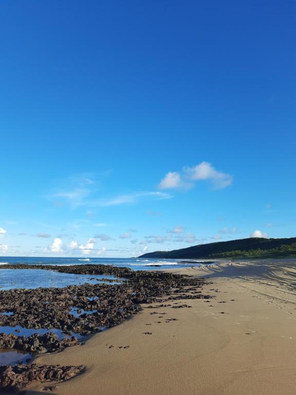 una playa con rocas y el océano en un día soleado en Casa Alto da Falésia, en Baía Formosa