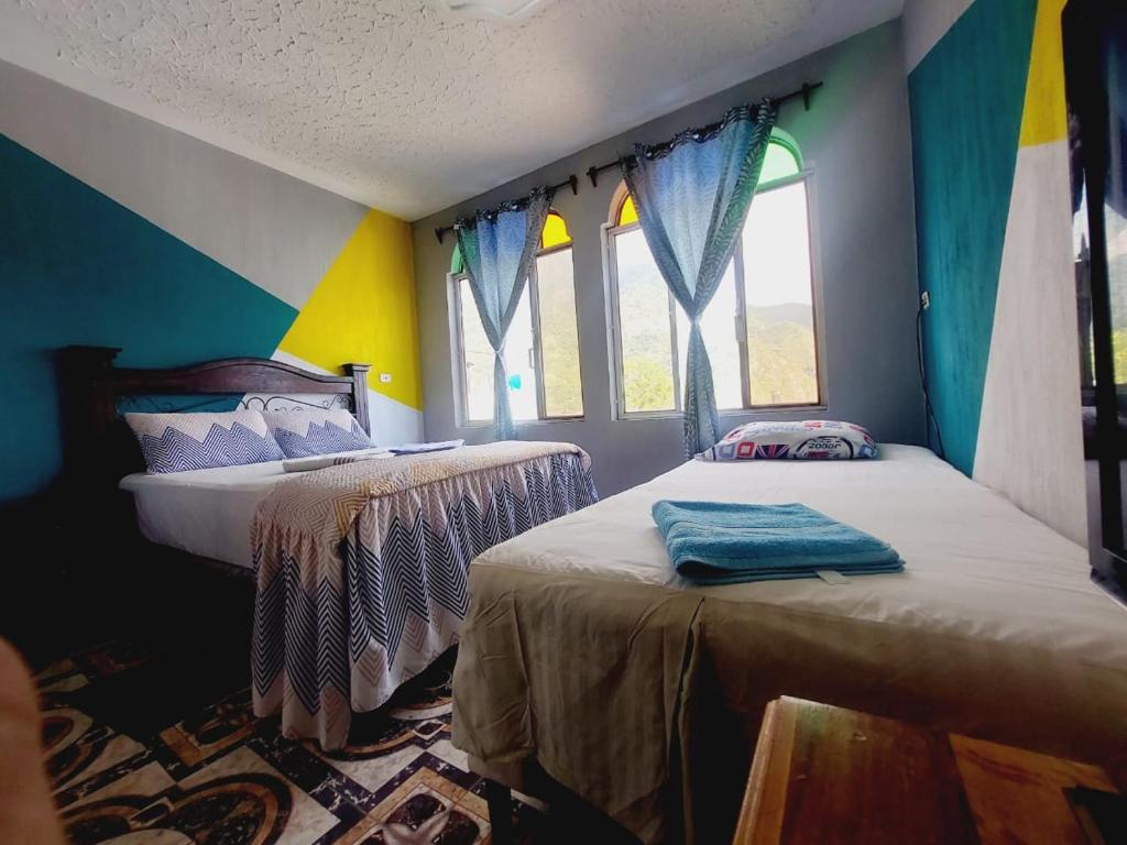 two beds in a room with colorful walls and windows at Alojamiento San Juan in San Juan La Laguna