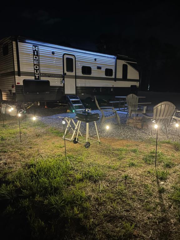 a campsite with a trailer and a table and chairs in front of a train at Mountain Top Hideout in Sevierville