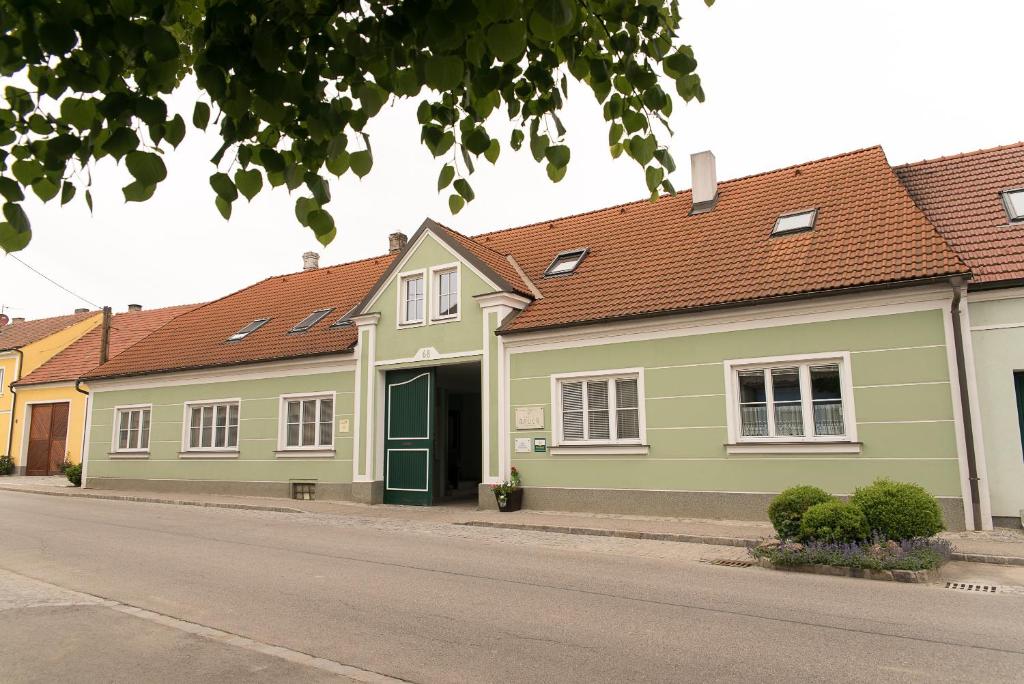una casa verde con techos rojos en una calle en Weingut Familie Bauer, en Großriedenthal