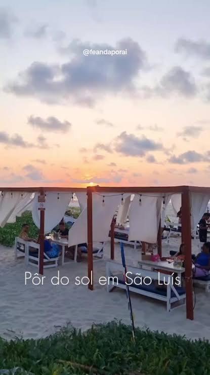 a group of chairs and umbrellas on a beach at Quarto em AP compartilhado Ponta da areia in São Luís
