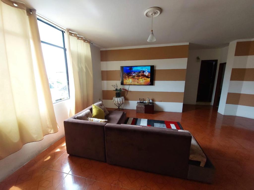 ein Wohnzimmer mit einem braunen Sofa und einem TV in der Unterkunft Departamentos de la Costa in Machala