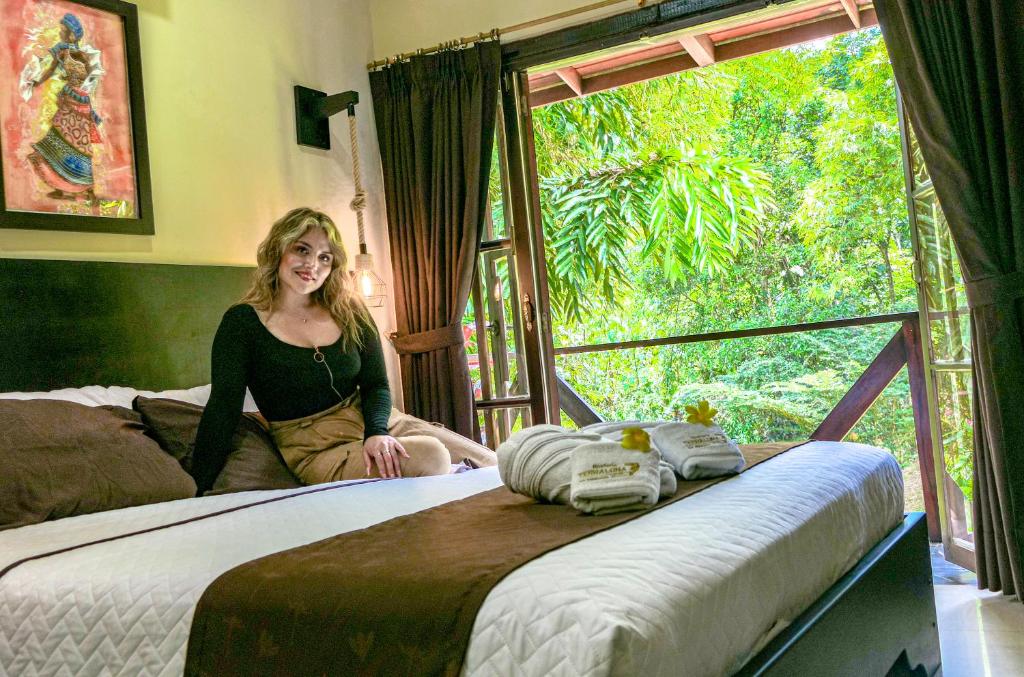 a woman sitting on a bed in a room with two beds at Terra Luna Lodge in Tena