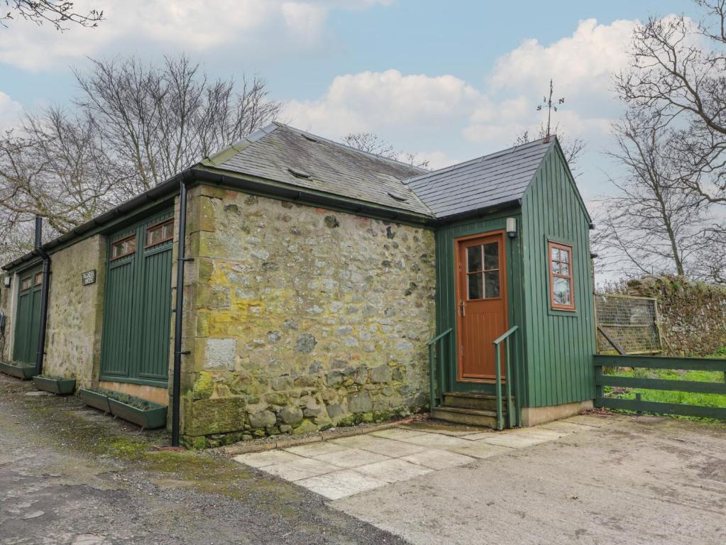 Un antiguo edificio de piedra con una puerta verde. en The Garden House, en Chirnside