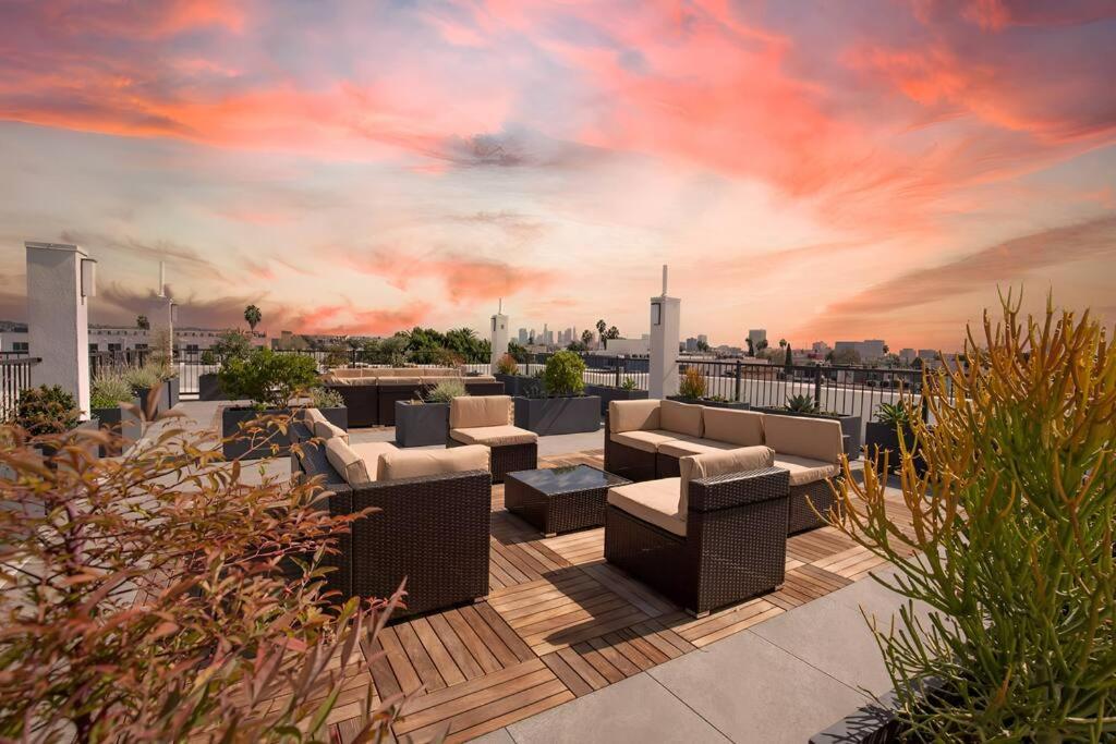 a rooftop patio with couches and tables and a sunset at Luxury at its Finest in Larchmont W. Roof Deck in Los Angeles