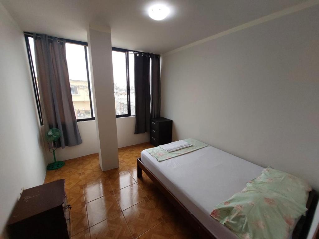 ein Schlafzimmer mit einem Bett in einem Zimmer mit Fenstern in der Unterkunft Departamentos de la Costa in Machala